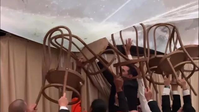 
                    Convidados de casamento usam cadeiras para segurar tenda devido à chuva
                