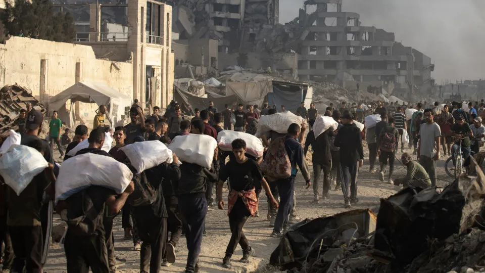 Displaced Palestinians carry relief parcels along Rashid Street, west of Gaza City