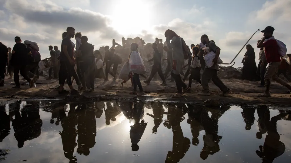 Displaced Palestinians carry relief parcels along Rashid Street, west of Gaza City