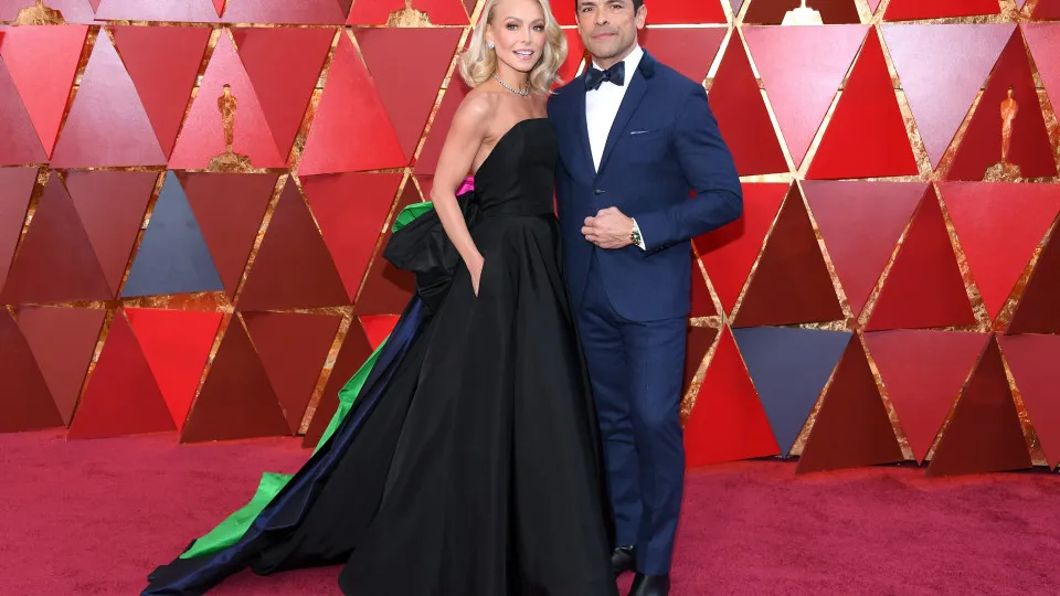 A apresentadodora&nbsp;Kelly Ripa casou furor no red carpet ao chegar com um longo vestido preto com enormes la&ccedil;os verde e rosa, em uma releitura dos look dos anos 80. Mark fugiu do cl&aacute;ssico e usou um&nbsp;smoking azul marinho.