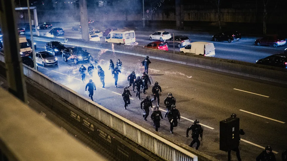 CRS riot police and fireworks explode on the peripheral boulevard as Paris Saint Germain PSG fans celebrate their team s victory after the second leg of the UEFA Champions League semi final match between Paris Saint Germain PSG and Arsenal at Place de la 
