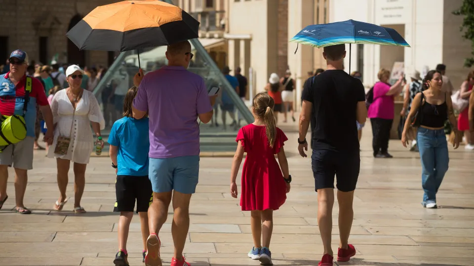 MALAGA, SPAIN. - 05 AUG:  Tourists hold umbrellas to protect themselves from the sun as they walk during a hot summer day in Malaga, Spain, on 05 August, 2025. Spain is experiencing a widespread rise in temperatures due to a new heatwave, with yellow and 