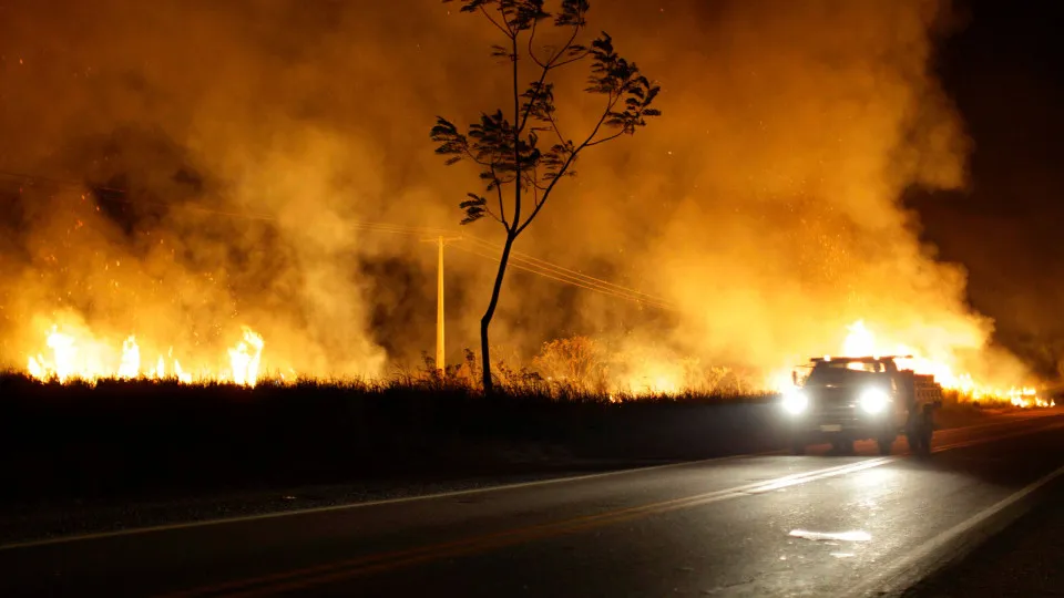 Carro numa estrada com incêndio à volta.
