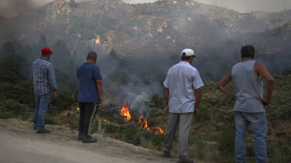 People watch the progress of a wildfire in Trancoso on August 11, 2025. In Portugal today firefighters were battling three large wildfires in the centre and north of the country. The largest, near the town of Trancoso, has been burning since August 9, 202