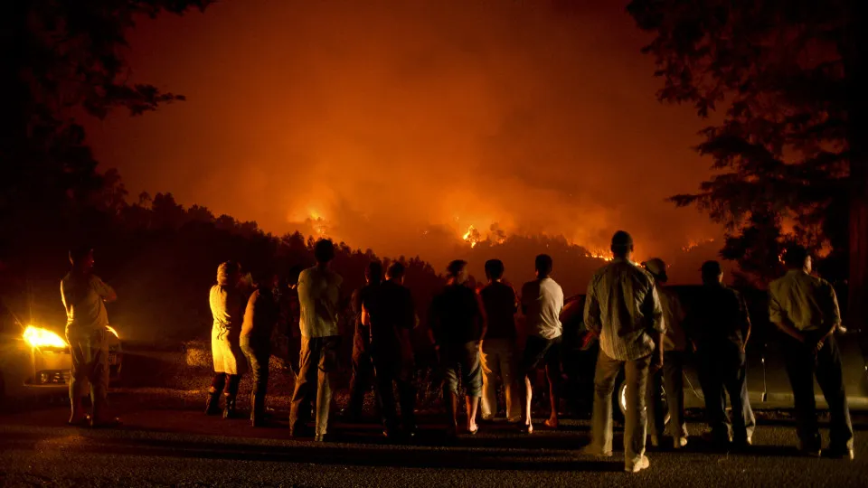 People stand watching a wildfire in Santiago de Besteiros, near Caramulo, central Portugal, on August 30, 2013. Five Portuguese mountain villages were evacuated overnight as forest fires intensified in the country's north and centre, officials said today.