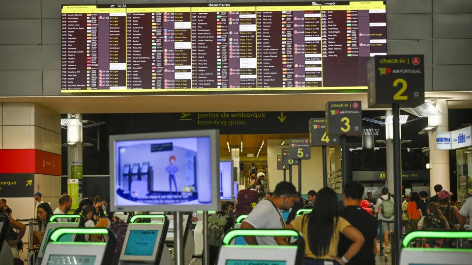 LISBON, PORTUGAL - AUGUST 09: Travelers use TAP Air Portugal self check-in machines under a large electronic billboard announcing flight delays and cancellations at the Terminal 1 Arrivals Hall on the second day of a ground staff strike at Humberto Delgad