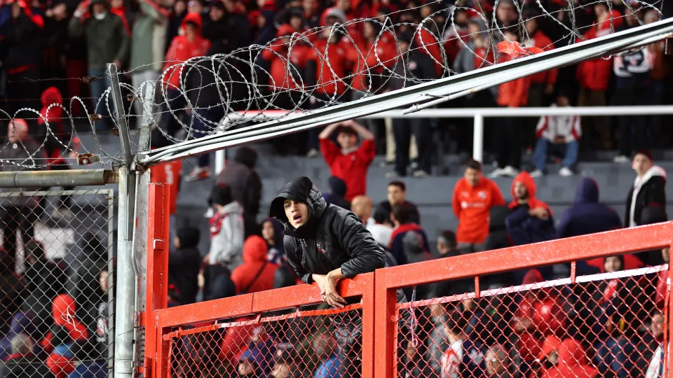 A fan of Independiente climbs a gate during the interruption of the Copa Sudamericana round of 16 second leg football match between Argentina's Independiente and Chile's Universidad de Chile at the Libertadores de America stadium in Avellaneda, Buenos Air